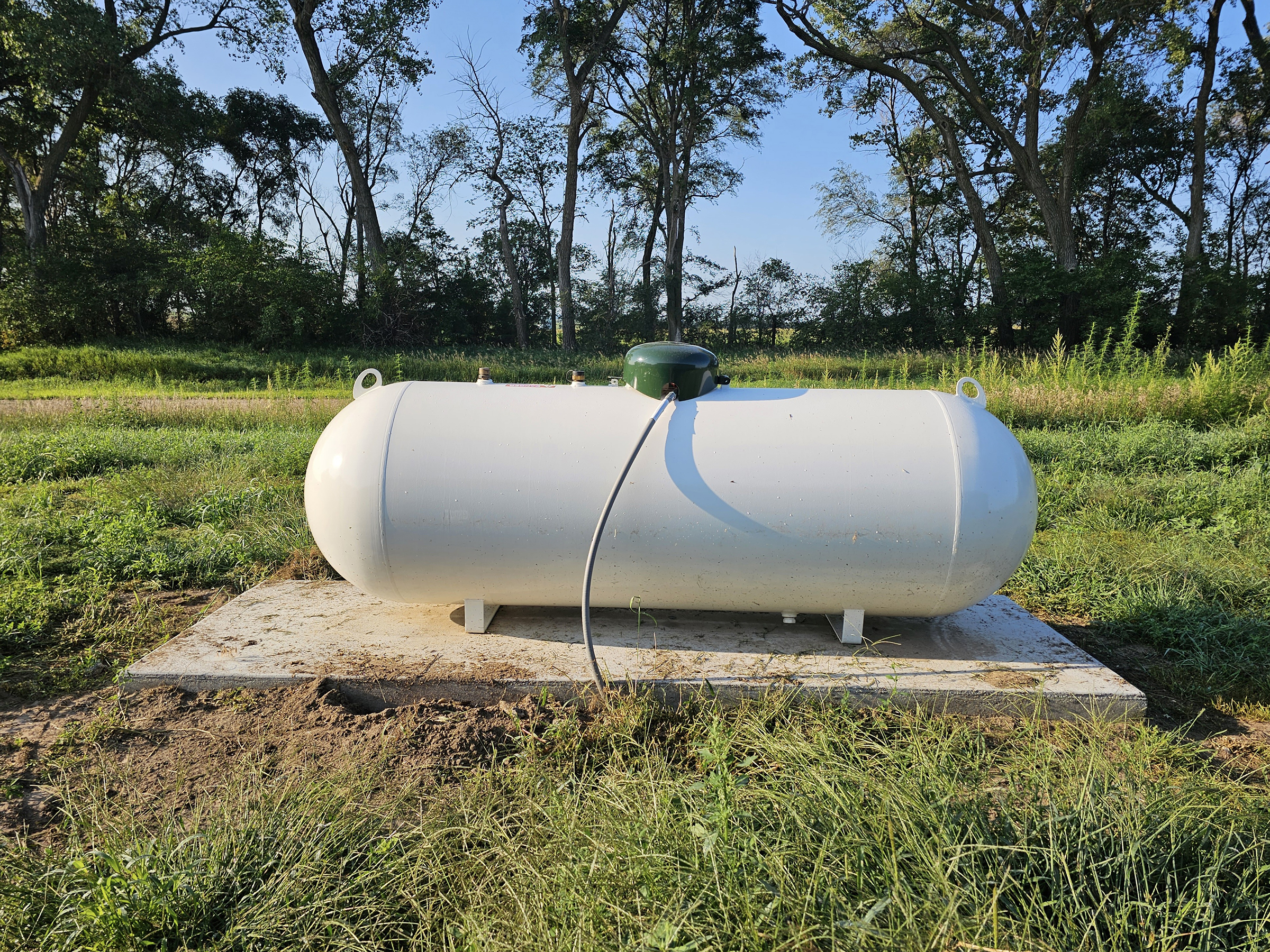 Two propane white canisters against brick wall.